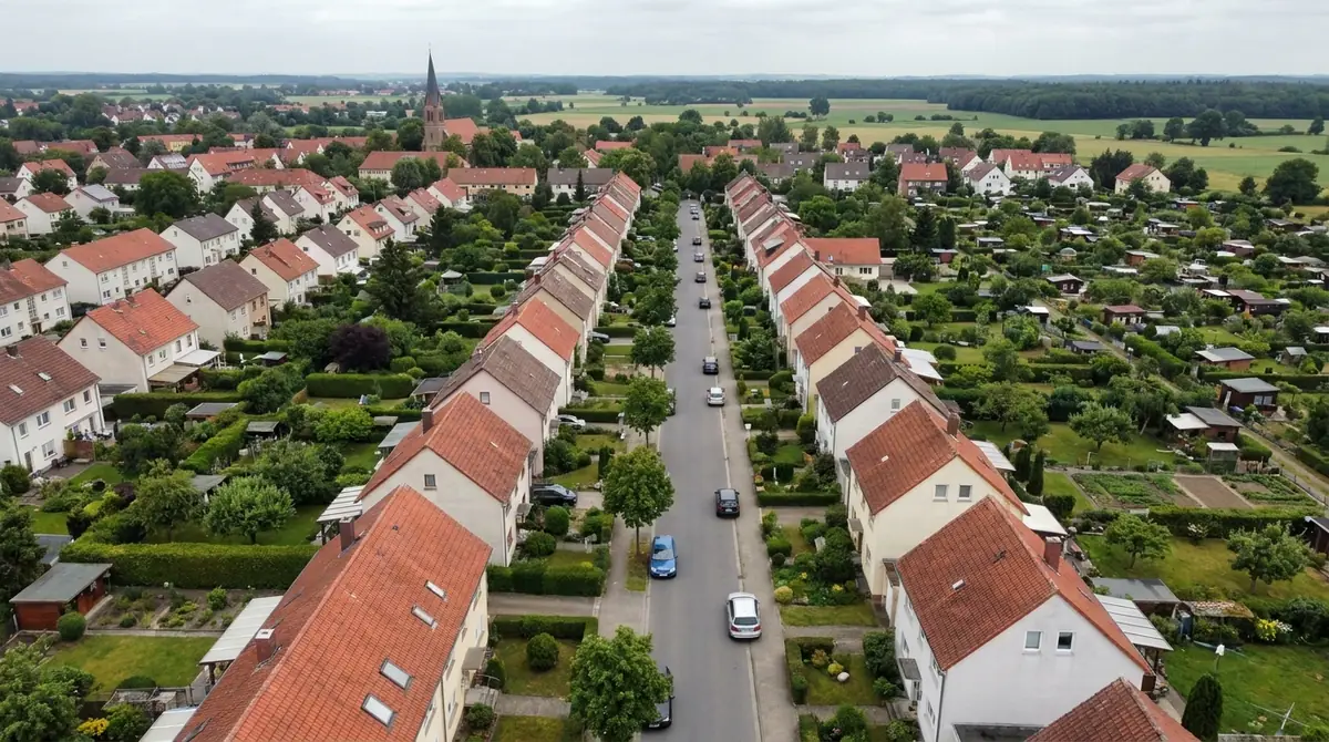 Luftbild einer Wohnsiedlung mit Reihenhäusern, Gärten und Kleingärten am Ortsrand